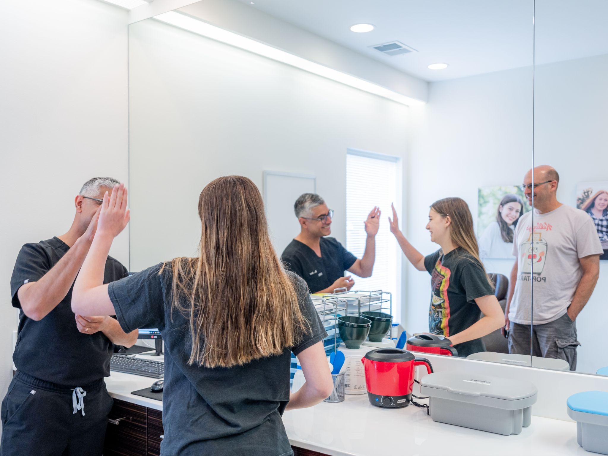 Doctor high-fiving teenage orthodontic patient